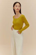woman in golden yellow cardigan and white pants