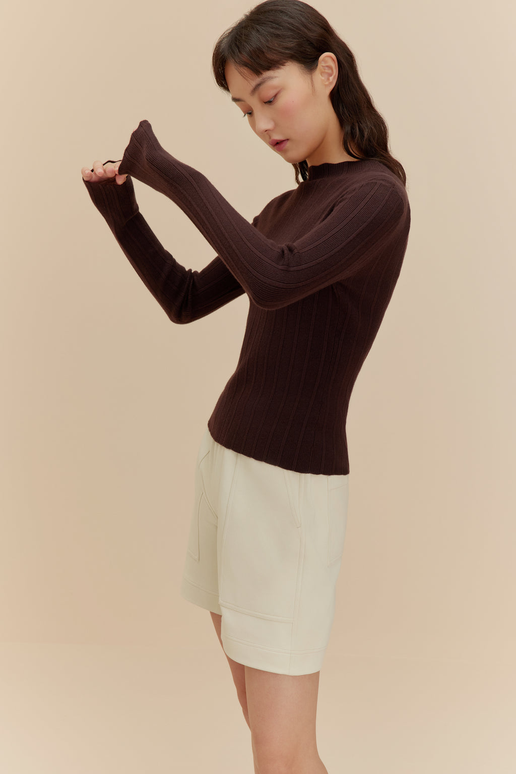 woman in brown sweater and white shorts