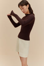 woman in brown sweater and white shorts