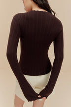 back of woman in brown sweater and white shorts