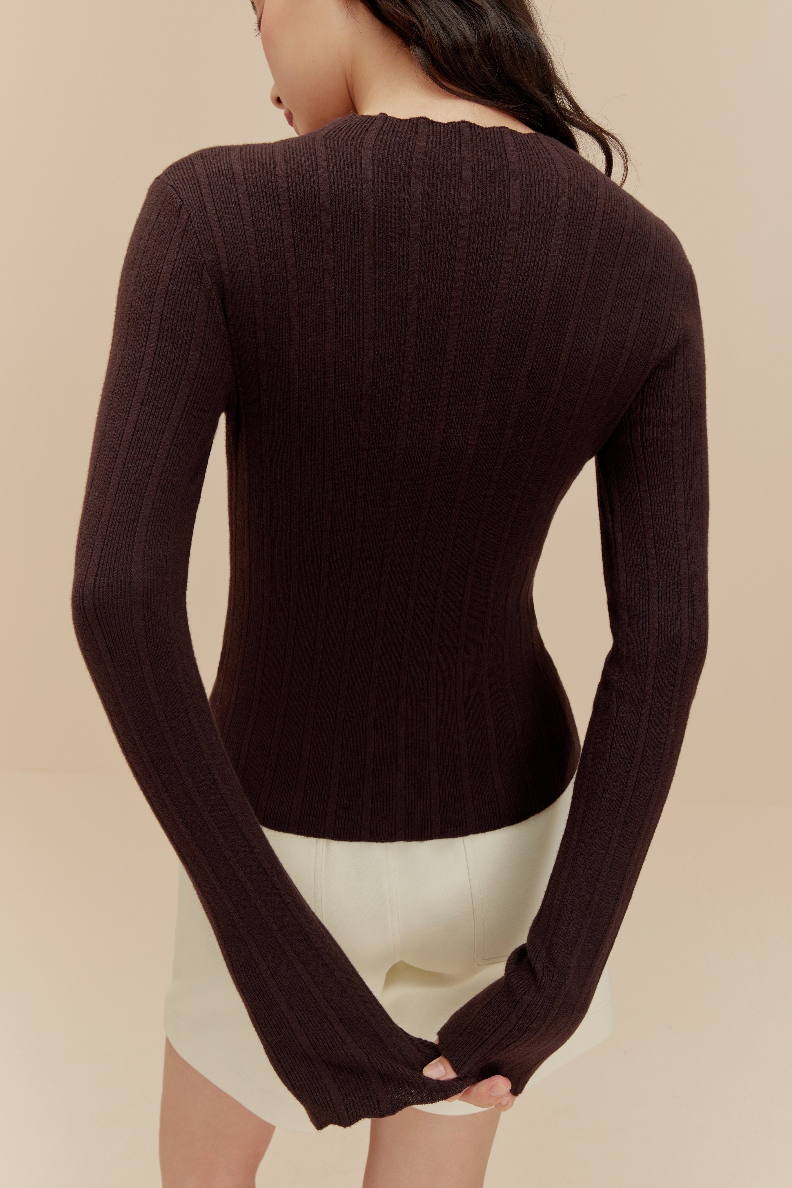 back of woman in brown sweater and white shorts