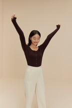 woman in brown cardigan and white pants