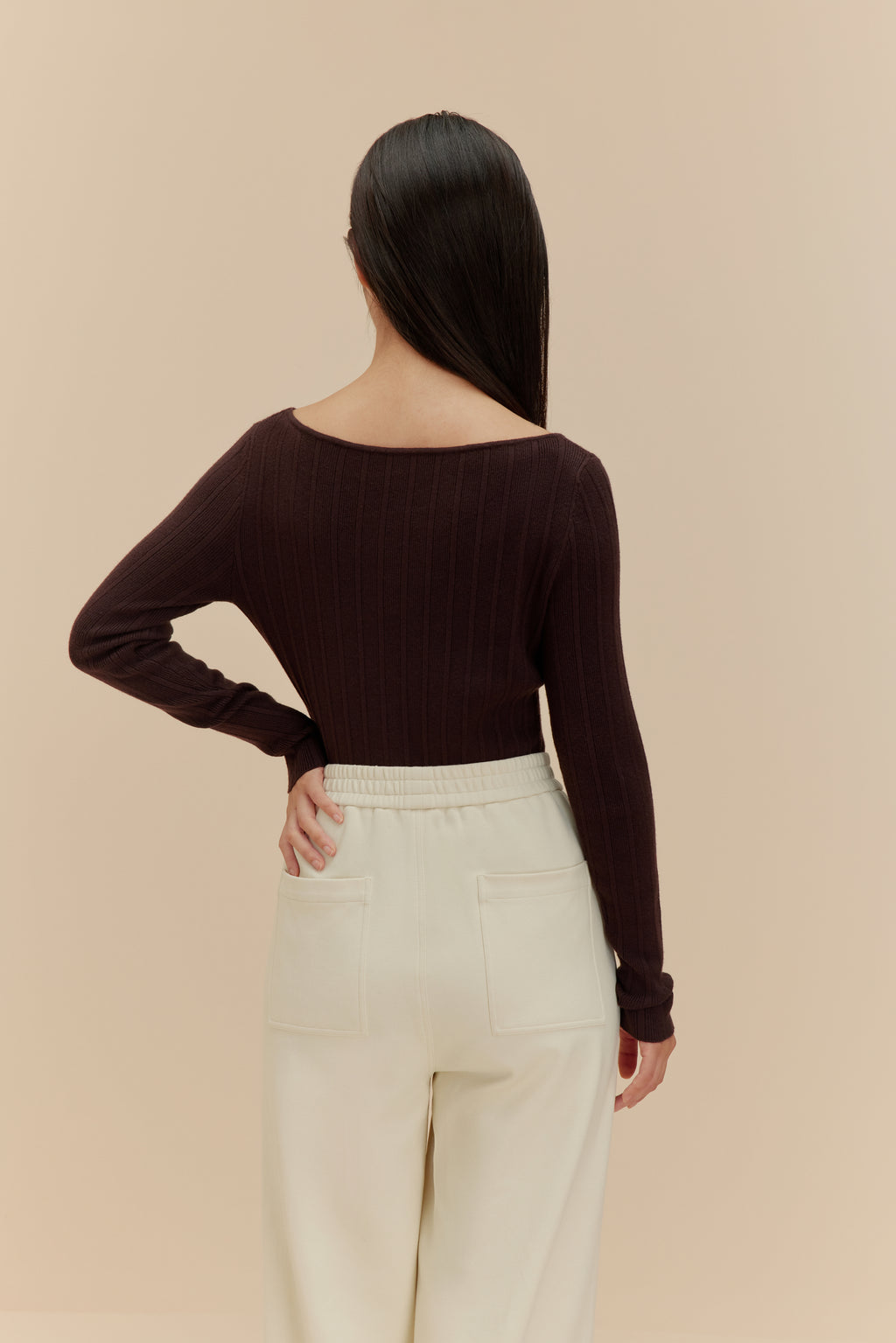back of woman in brown cardigan and white pants