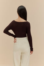 back of woman in brown cardigan and white pants