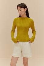 woman in golden yellow sweater and white shorts