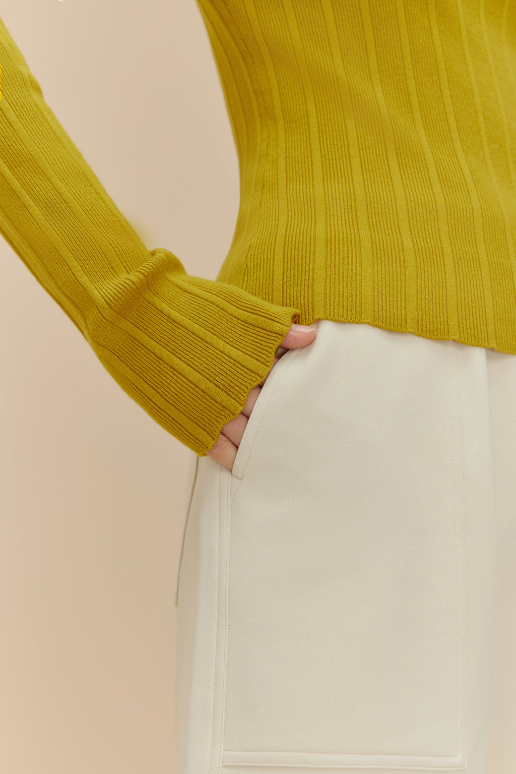 close up of woman in golden yellow sweater and white shorts