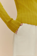 close up of woman in golden yellow sweater and white shorts