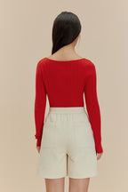 back of woman in red cardigan and white shorts