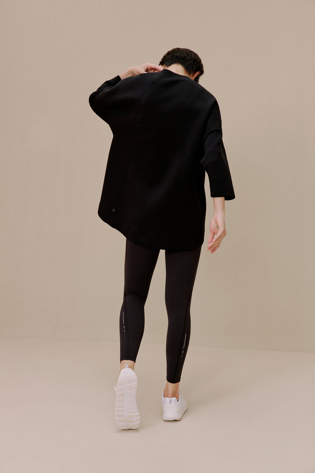 The back of a woman wearing a black top and black leggings