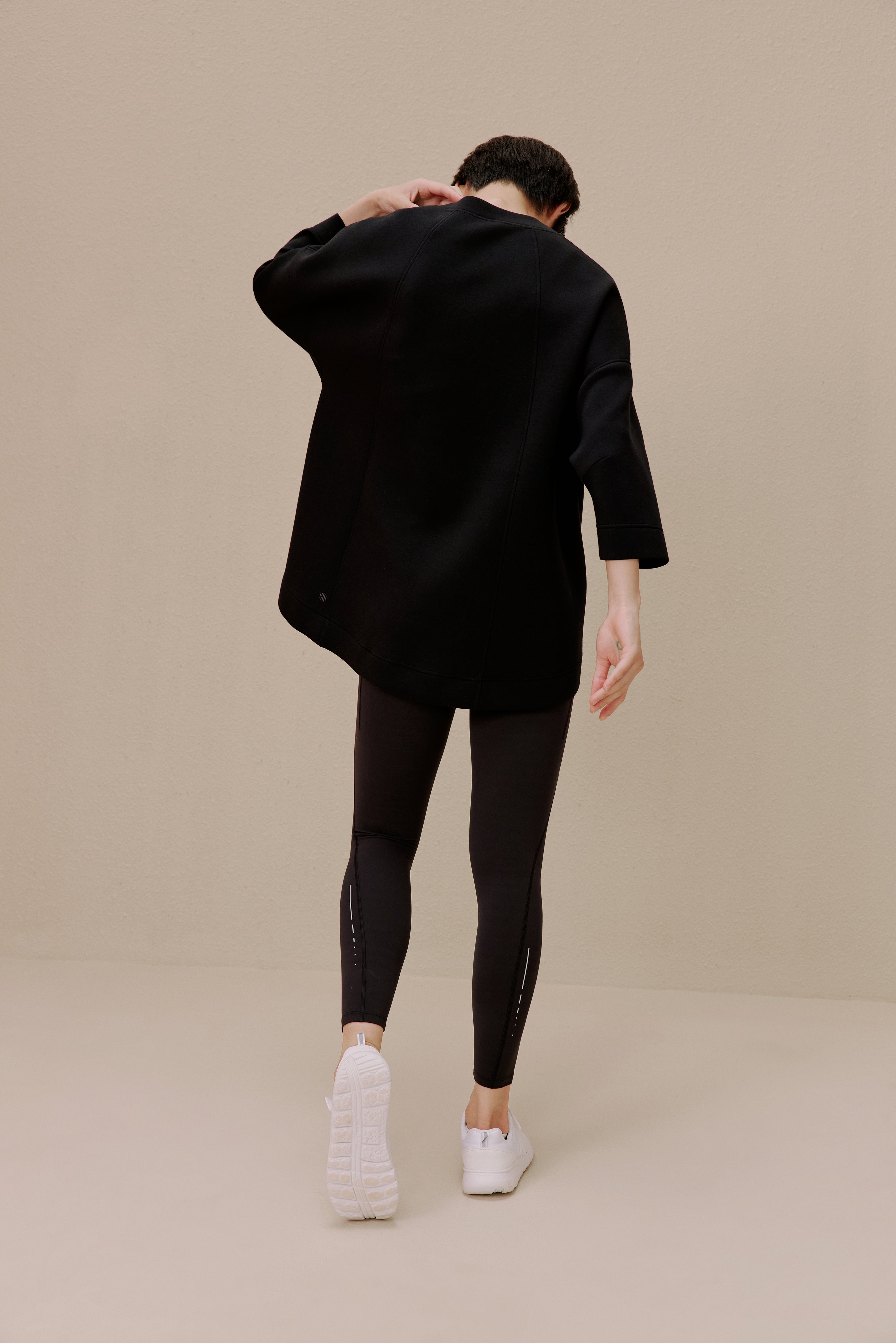 The back of a woman wearing a black top and black leggings