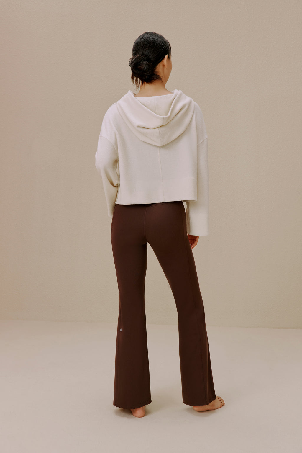 Back view of woman wearing white sweatshirt and brown wide-leg pants