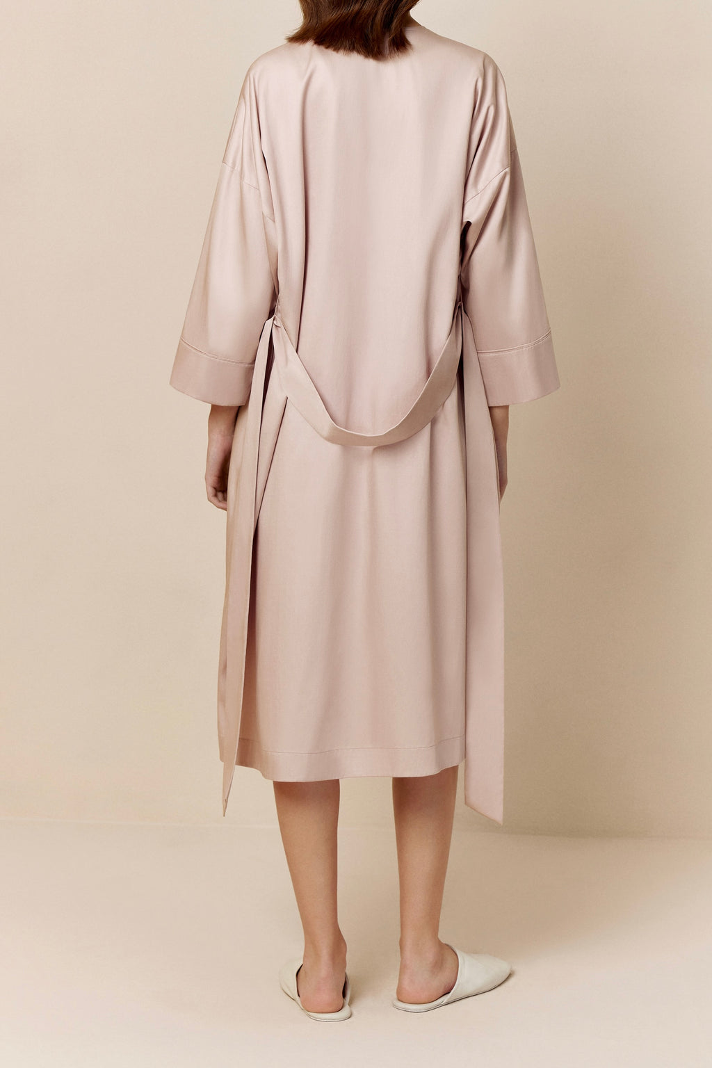 back of woman in light pink long pajama robe