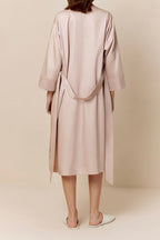 back of woman in light pink long pajama robe