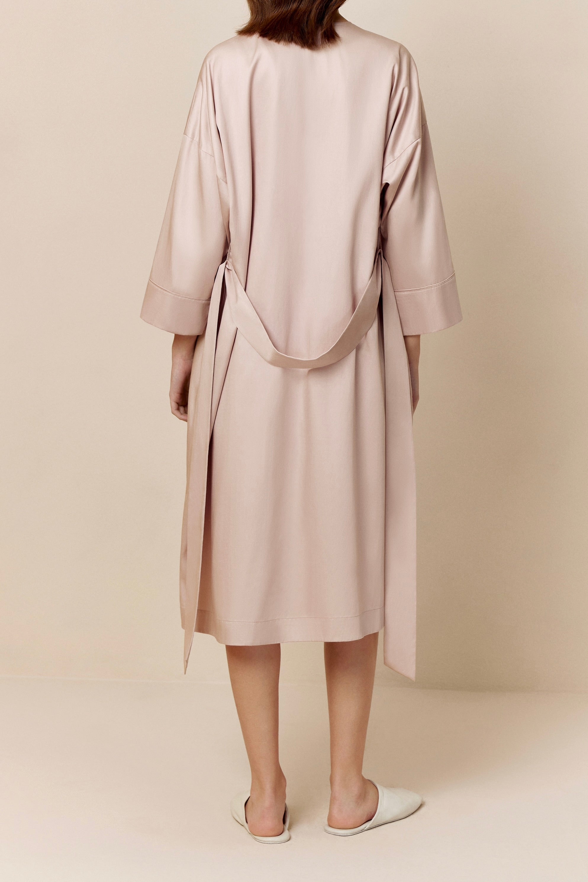 back of woman in light pink long pajama robe