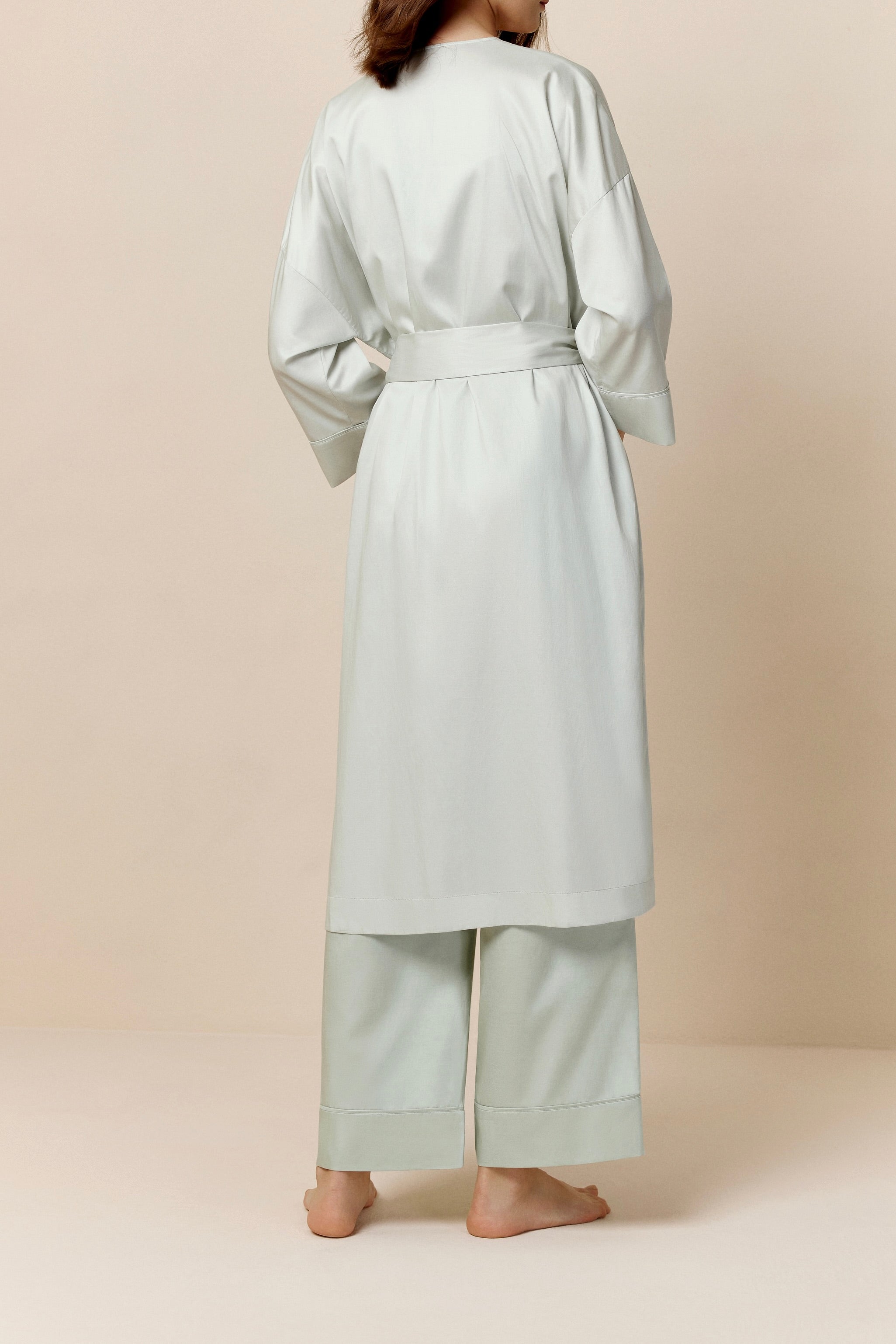 back of woman in light pink long pajama robe