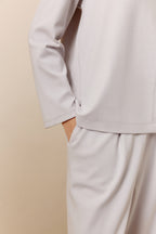 Close up view of woman in light gray top and pants.