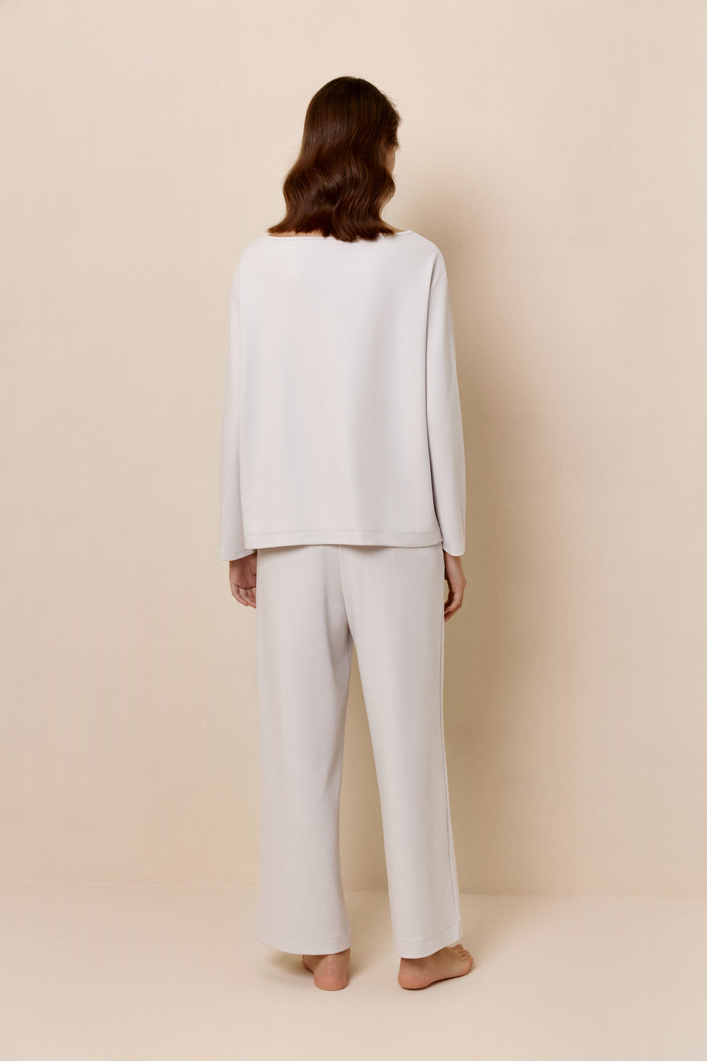 Back view of woman in light gray top and pants.