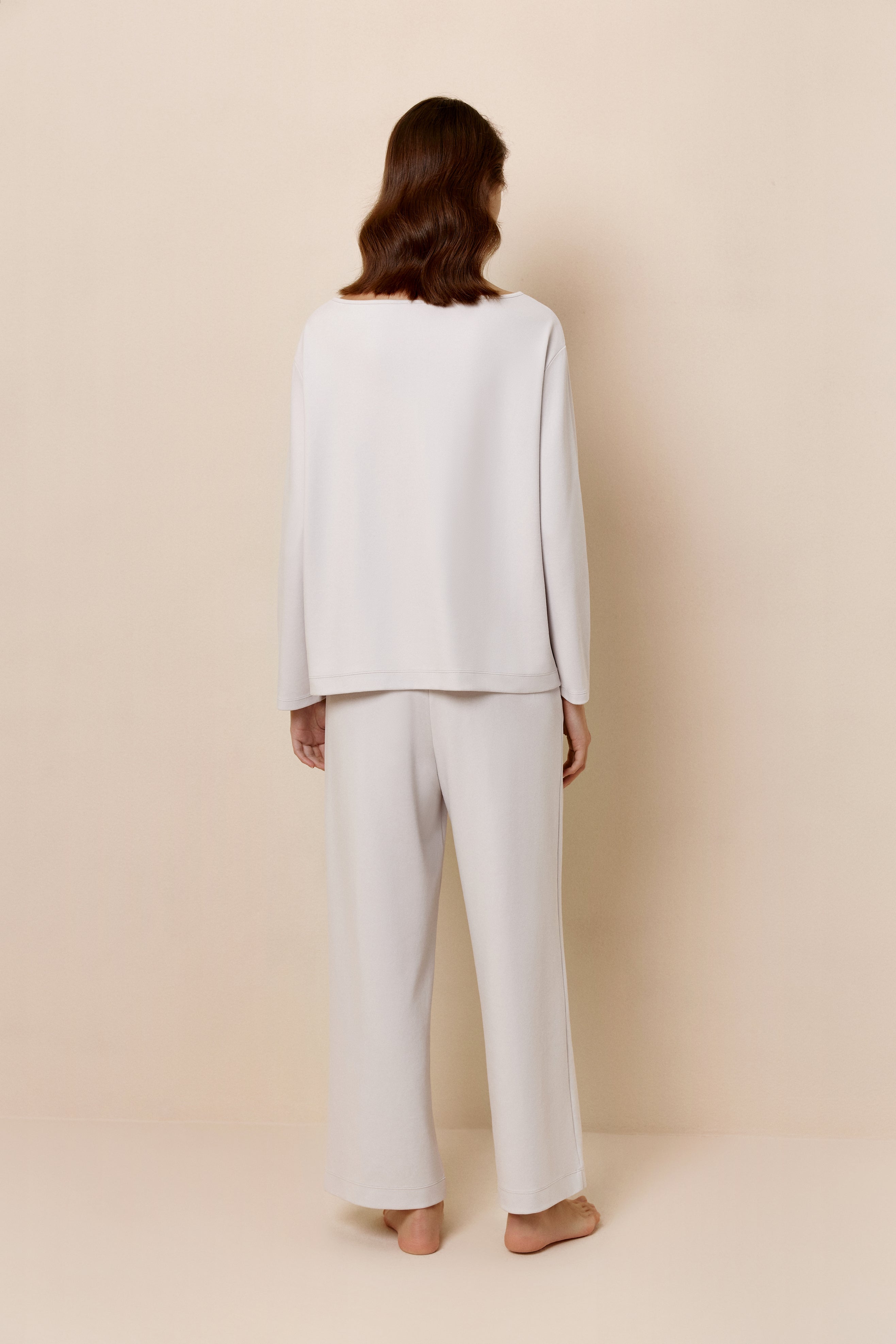 Back view of woman in light gray top and pants.