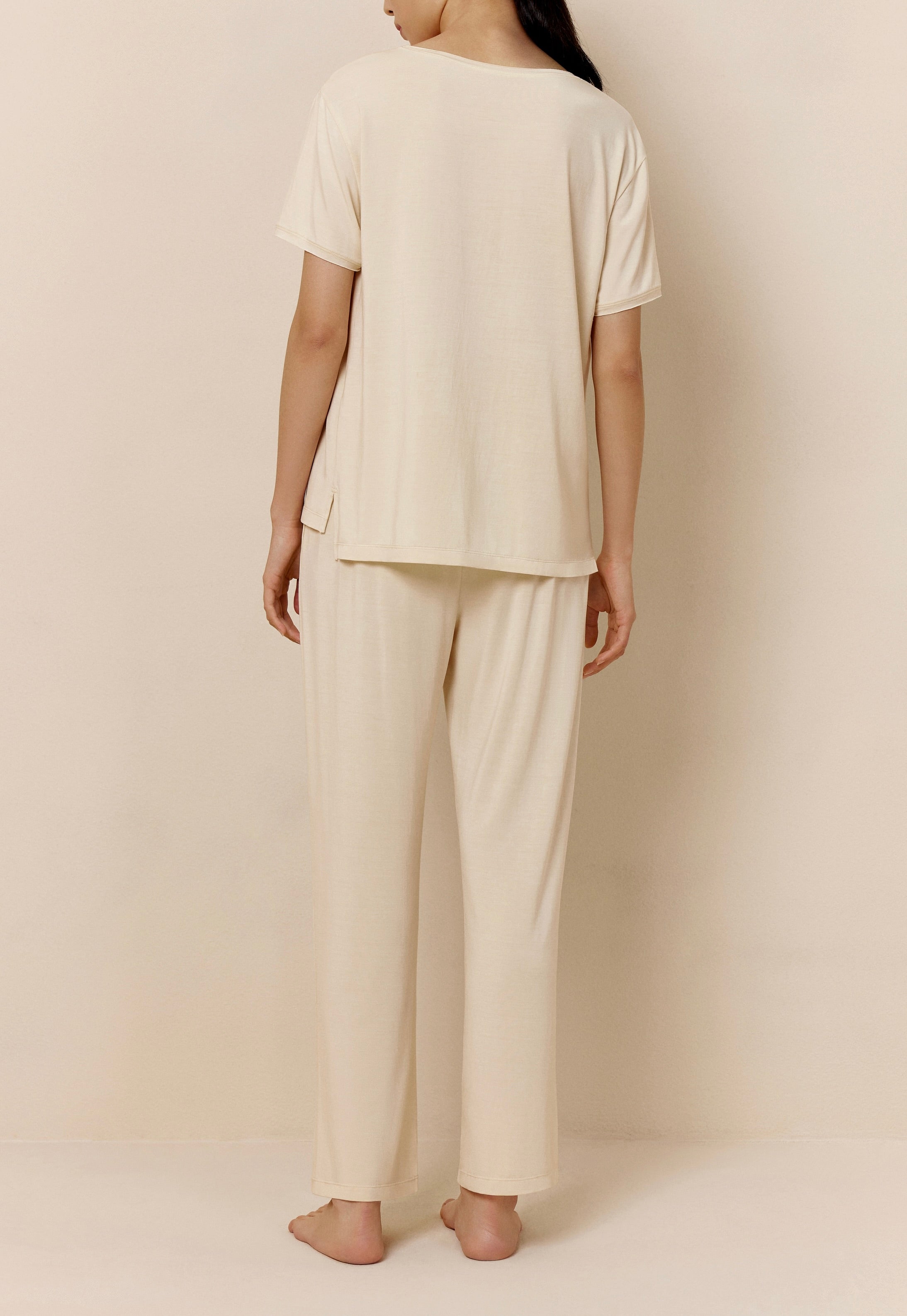 Back of woman wearing off-white short sleeve pajama shirt and matching pants