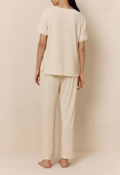 Back of woman wearing off-white short sleeve pajama shirt and matching pants