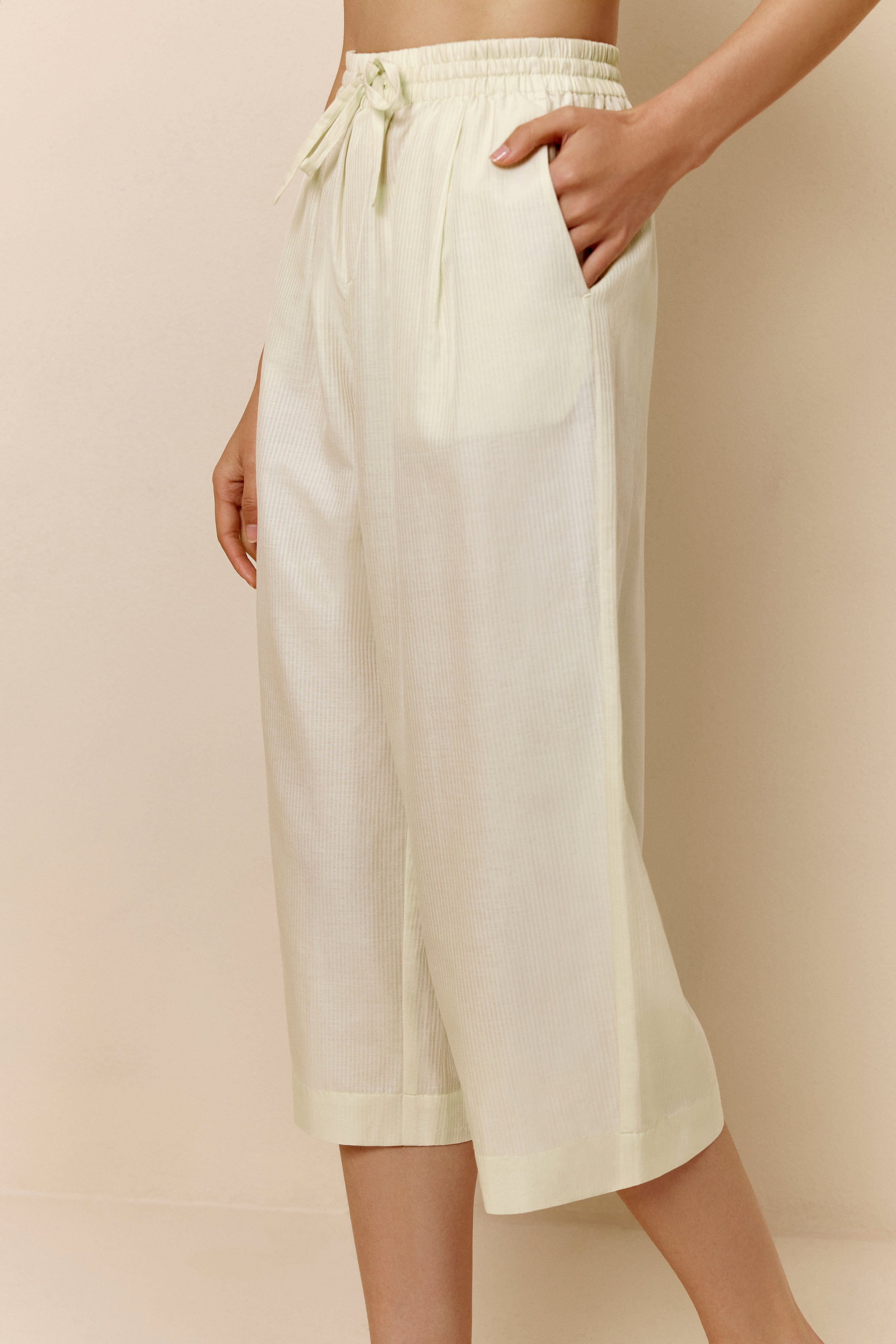 Bottom half of woman wearing off-white cropped pajama pants