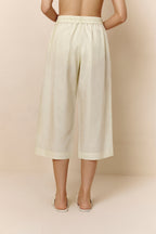 Back of bottom half of woman wearing off-white cropped pajama pants