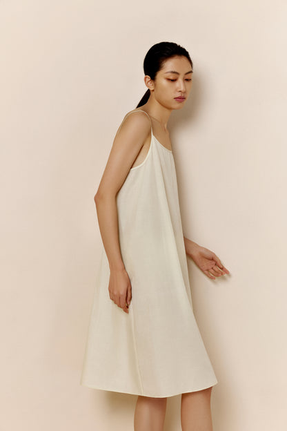 Side view of woman wearing off-white spaghetti strap pajama dress