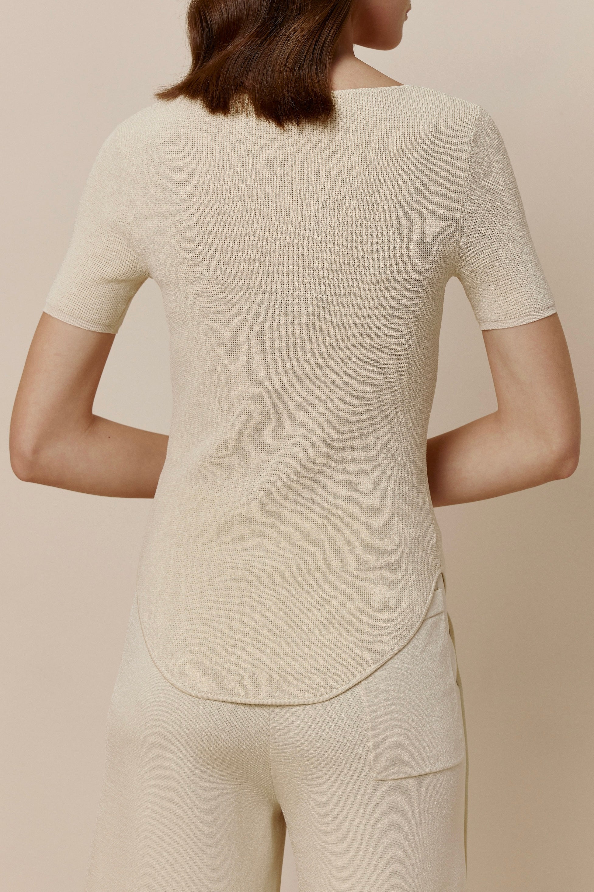 Back view of woman in off-white short-sleeved shirt