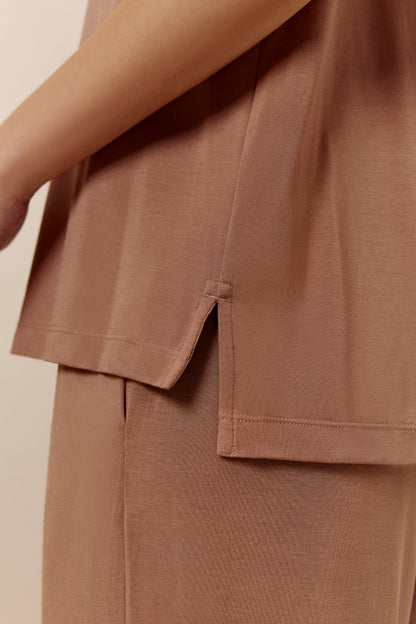 Close-up of hem of woman wearing dusty rose short sleeve pajama shirt showing small side slit