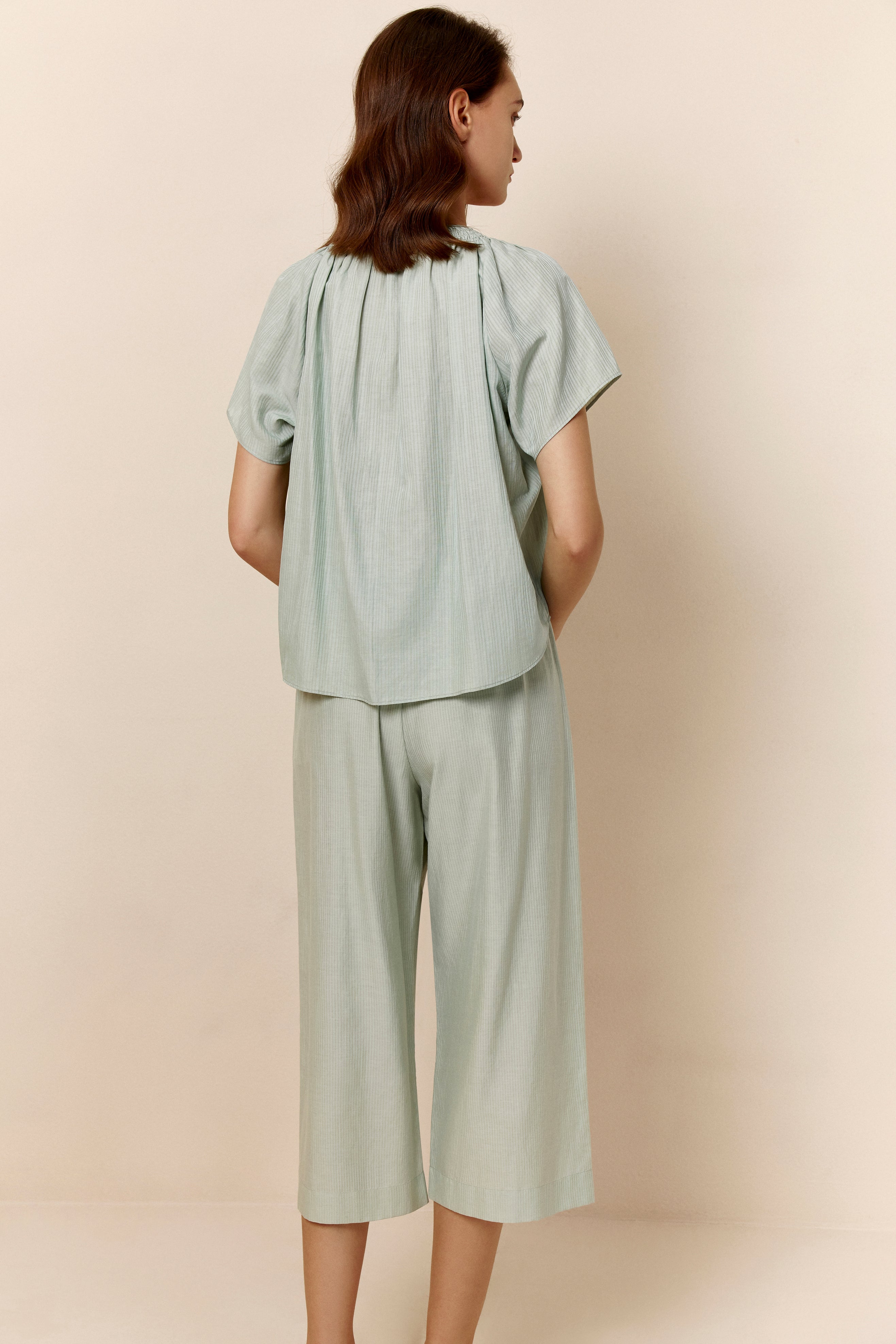 Back of woman wearing seafoam green top and cropped pajama pants