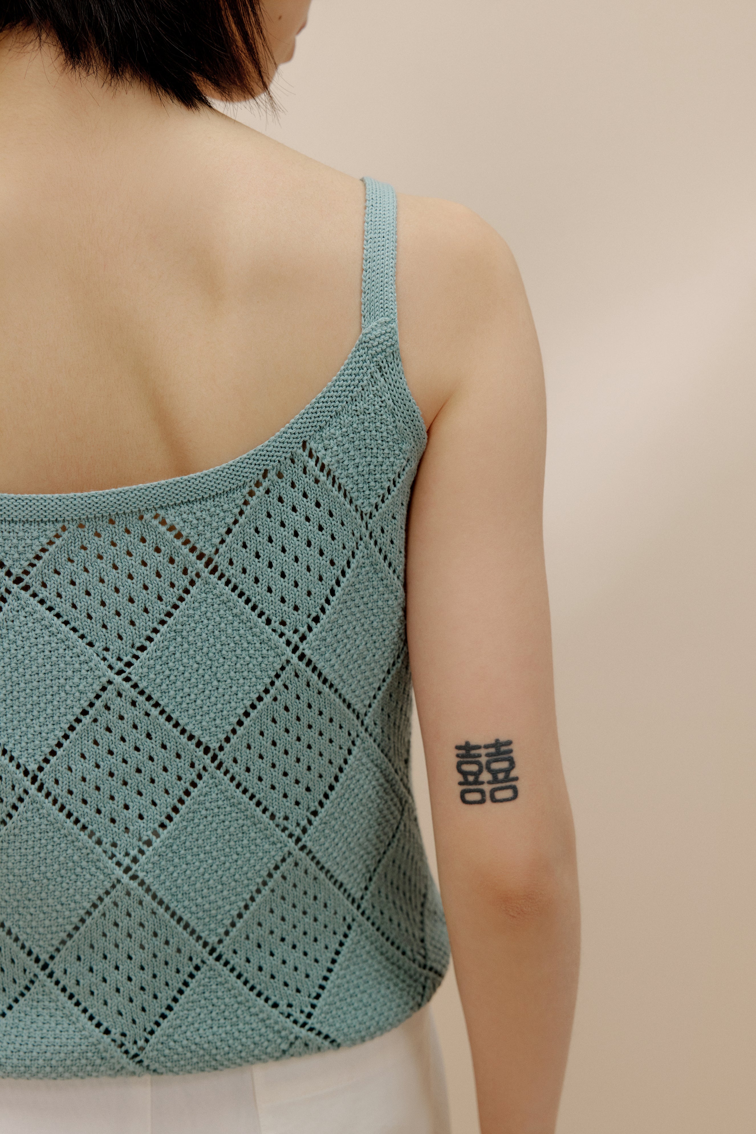 Back view of woman wearing blue crochet tank top.
