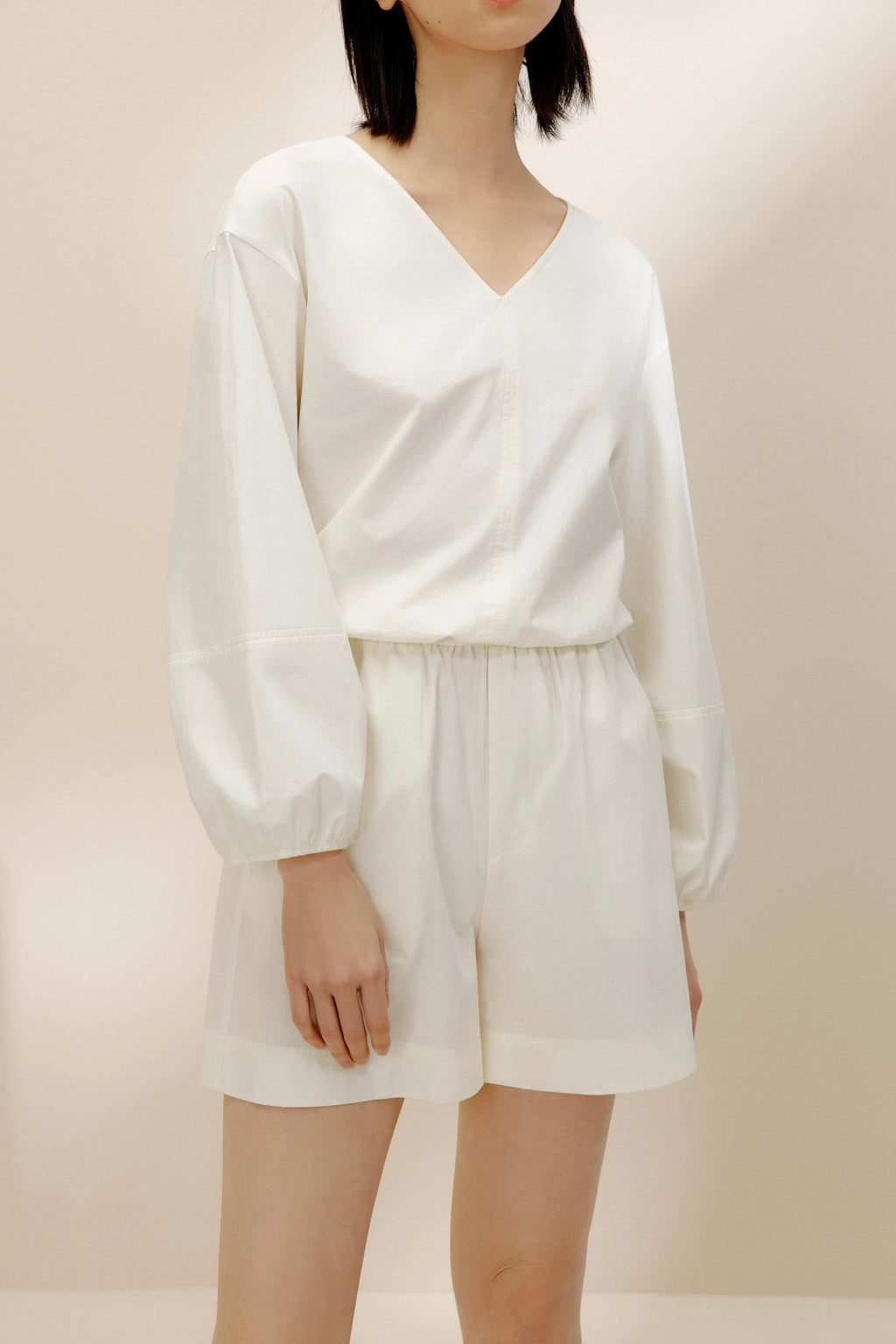 Front view of woman in white top and shorts.