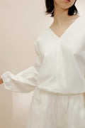 Front view of woman swinging her arm in white top.