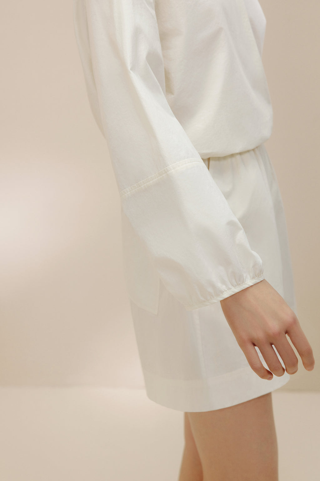 Side view of woman wearing white top and shorts.