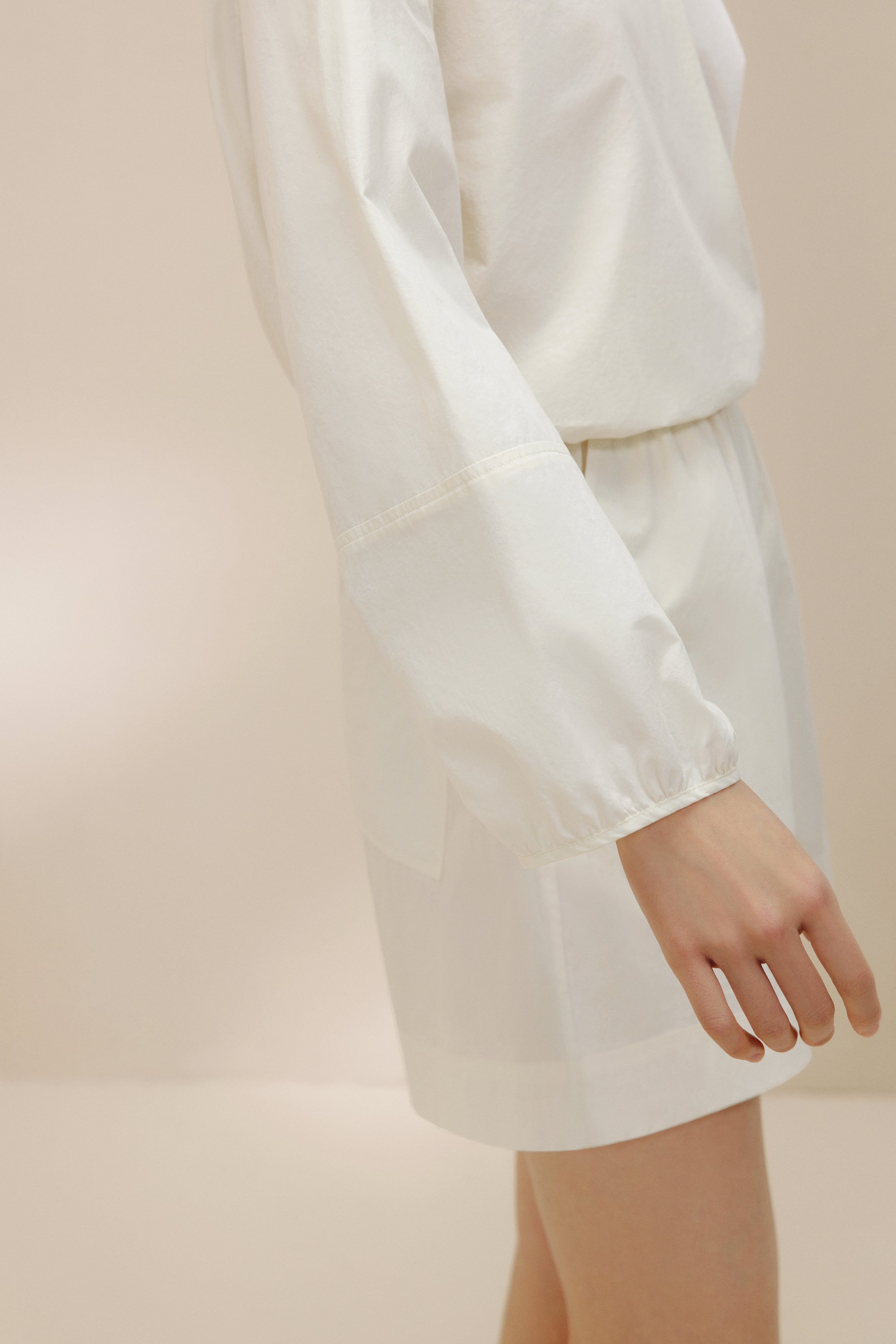Side view of woman wearing white top and shorts.