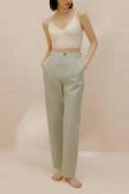 Front view of model wearing light green pants with cream bra top.
