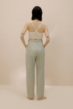 Back view of model wearing light green pants with cream bra top.