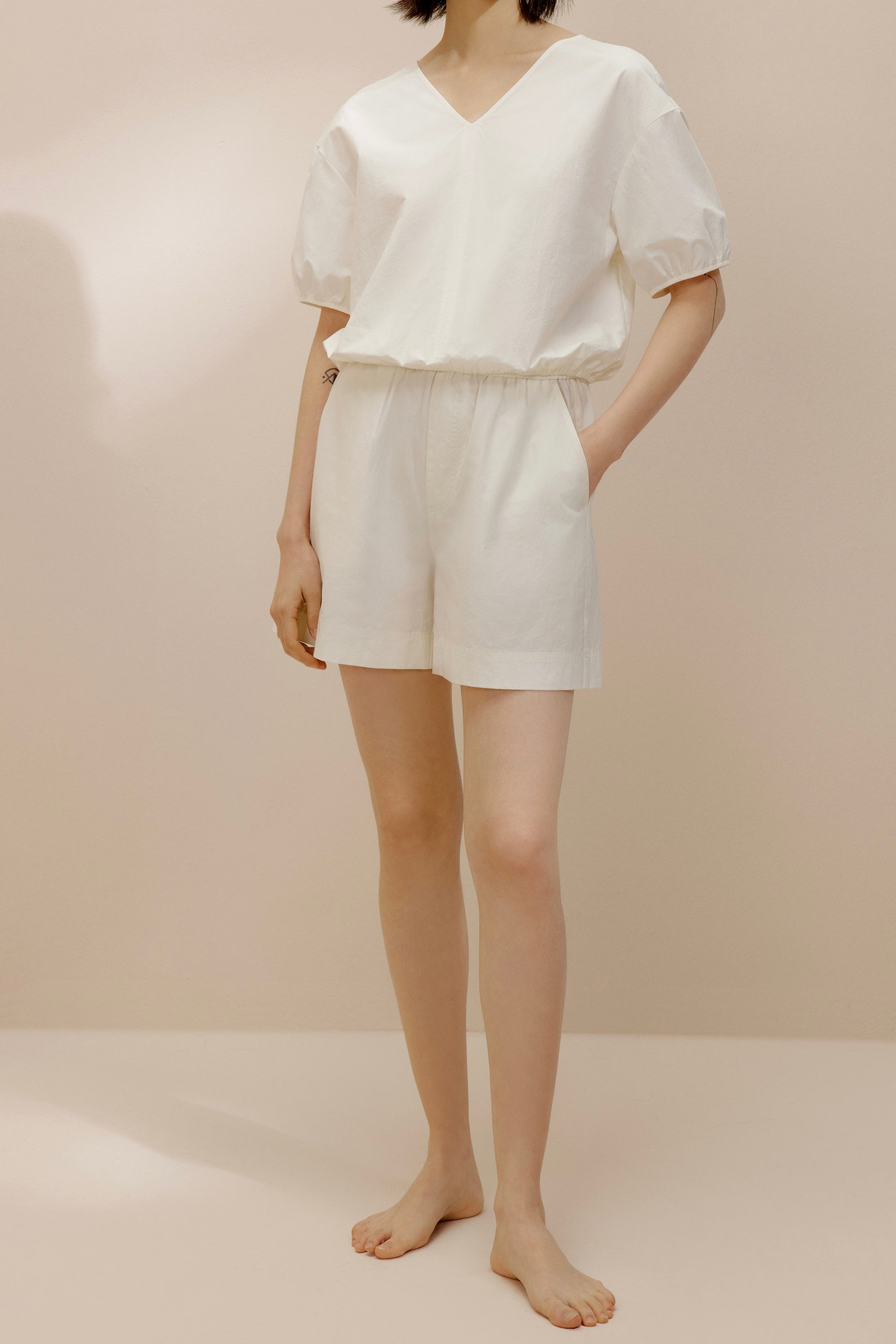 Front view of model wearing white top and white shorts.
