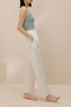 Side view of model wearing gray bra top putting hands into white pants pocket.