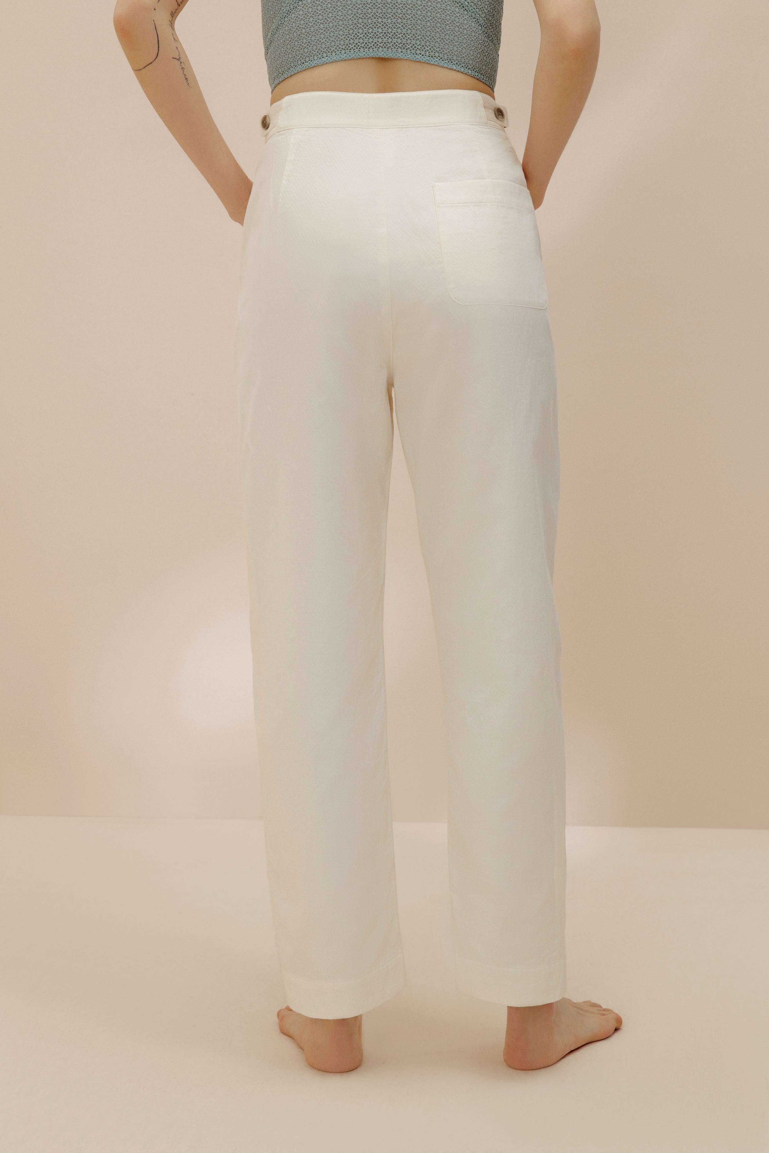 Back view of model wearing white pants.