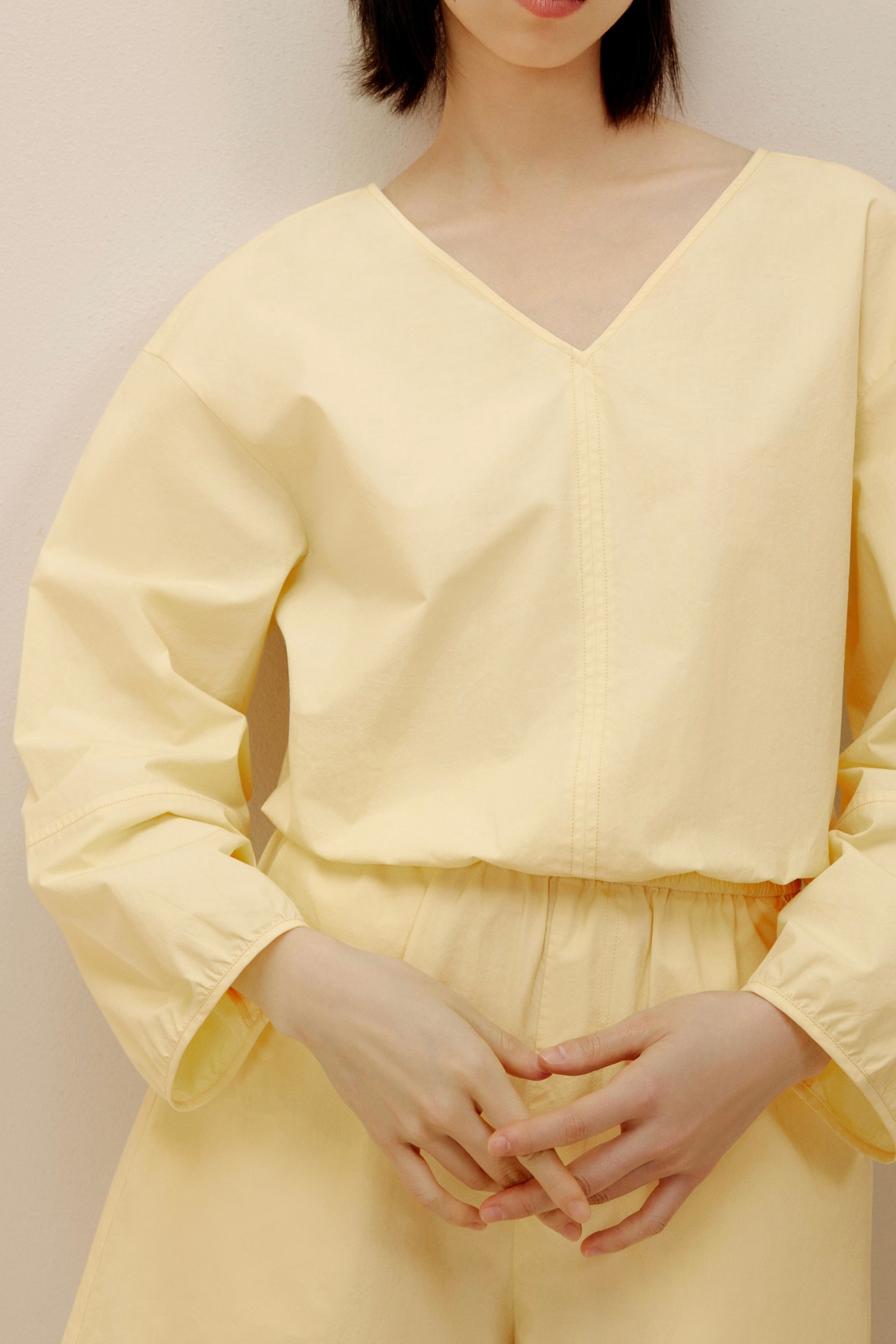 Woman wearing yellow long-sleeved top.