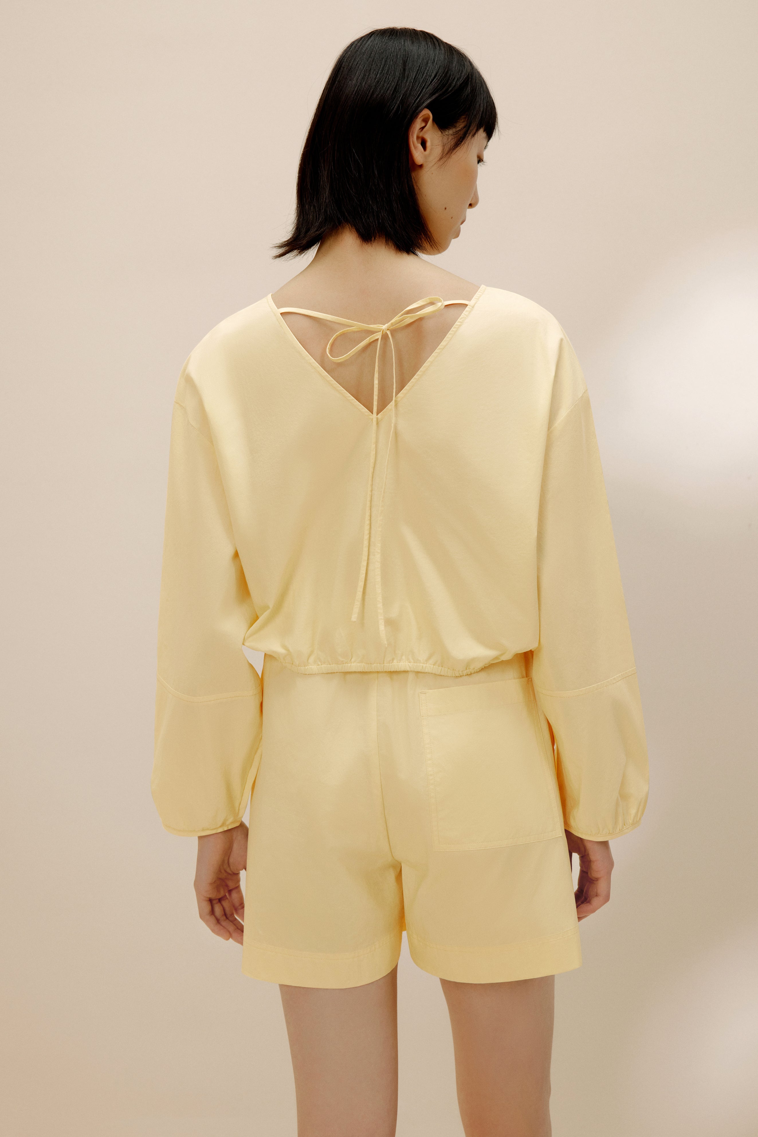 Back view of woman in yellow top and yellow shorts.
