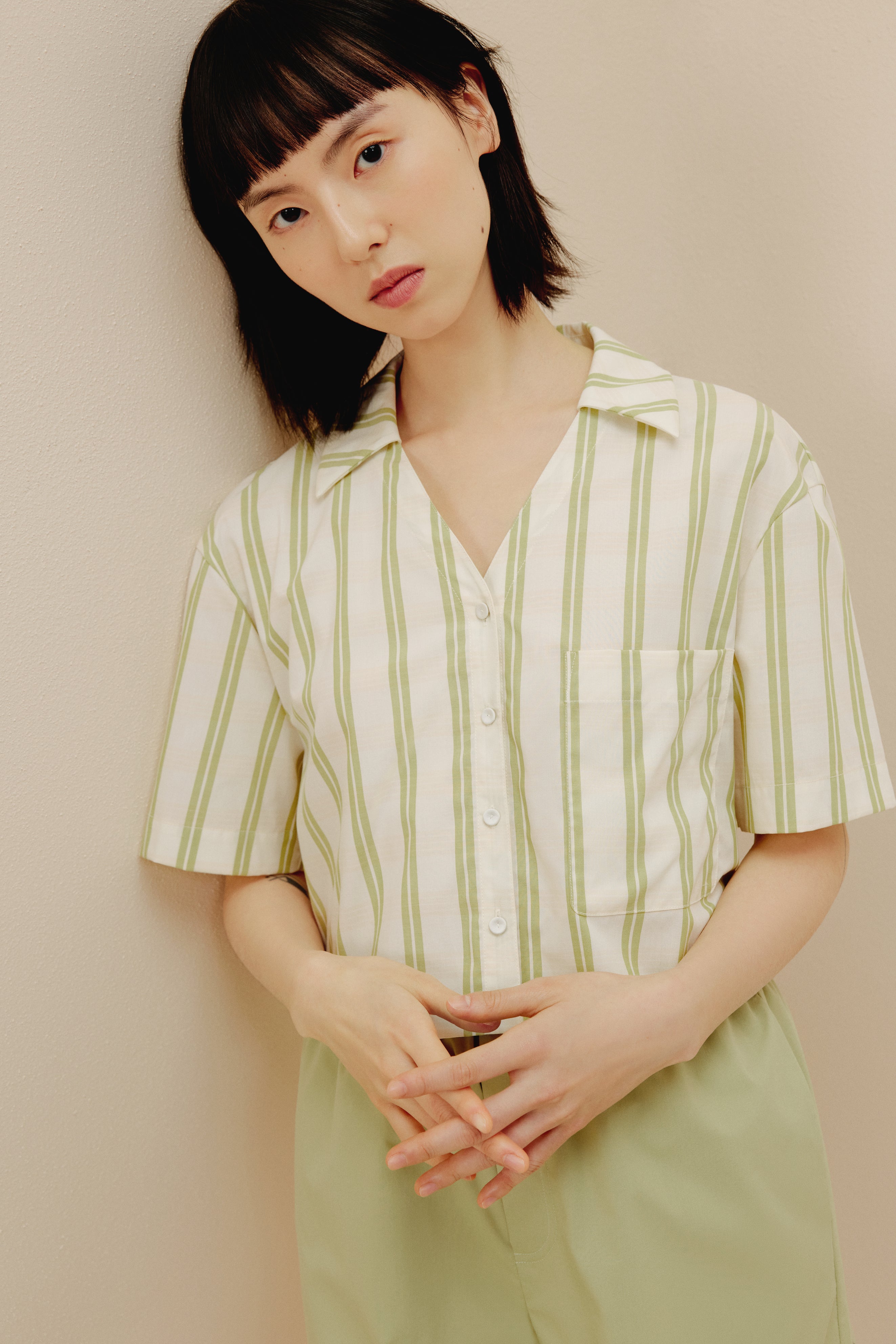 Woman wearing white and green short sleeved button up shirt and green pajama shorts