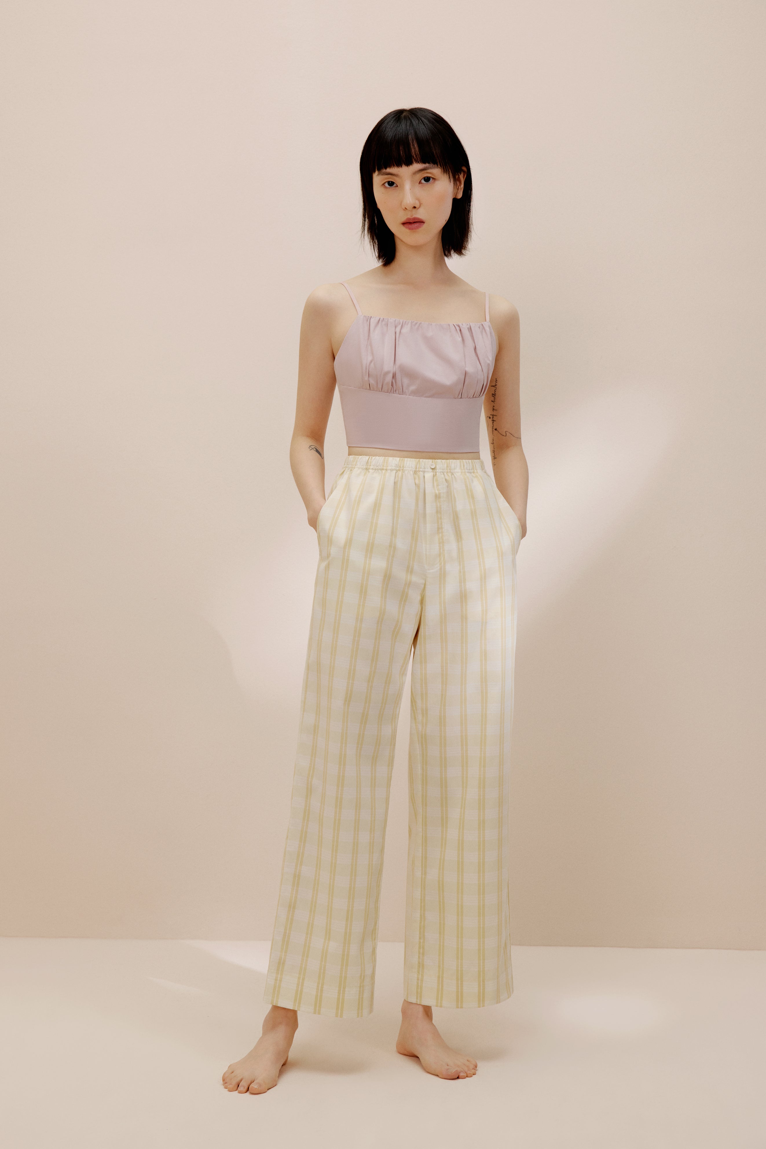 Woman wearing pink tank top and white and orange striped pajama pants