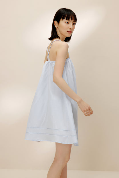 Side view of woman wearing light blue pajama dress.