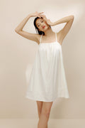 Woman wearing cream-colored cotton pajama dress.