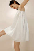 Side view of woman wearing cream-colored slip dress.