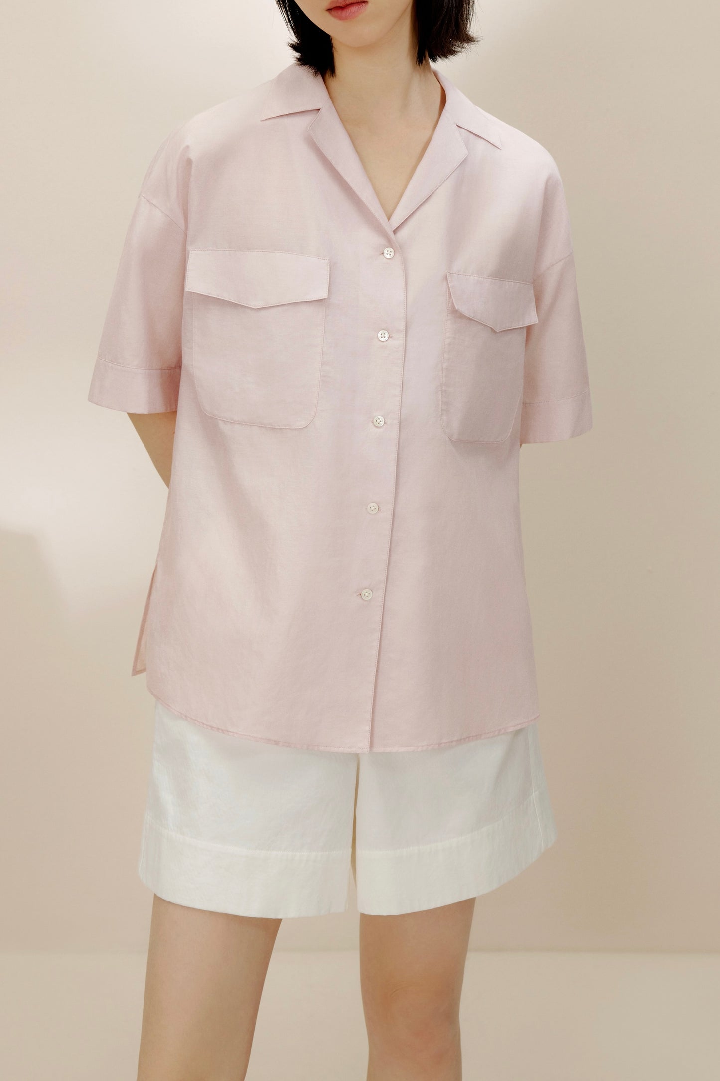 Front view of model wearing light purple shirt with white shorts.