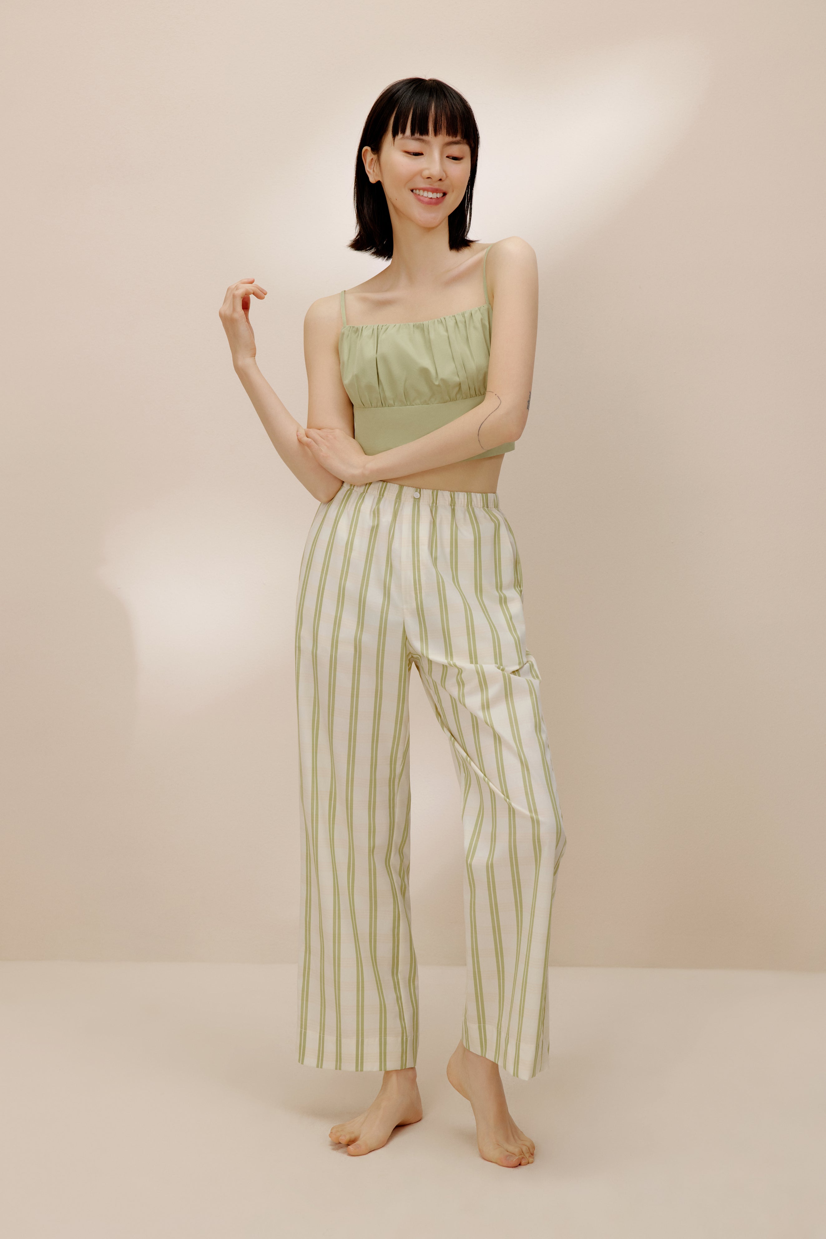 Woman wearing green tank top and white and green striped pajama pants