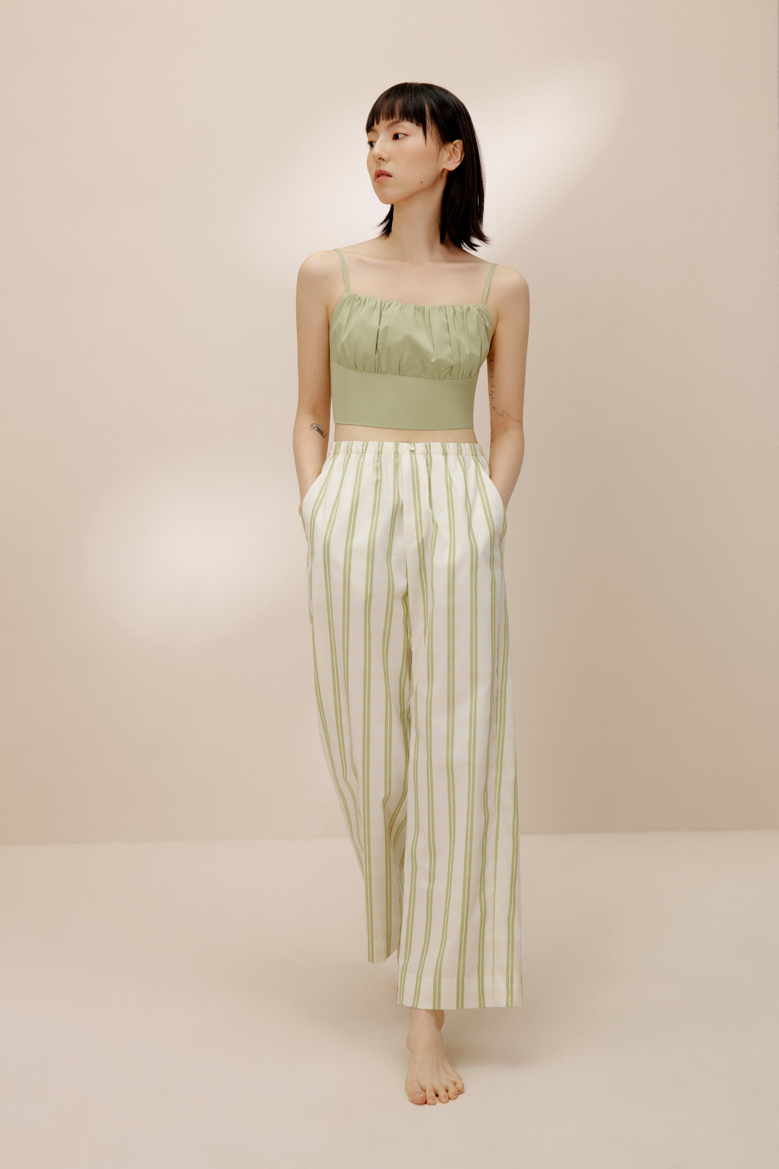 Woman wearing green tank top and white and green striped pajama pants